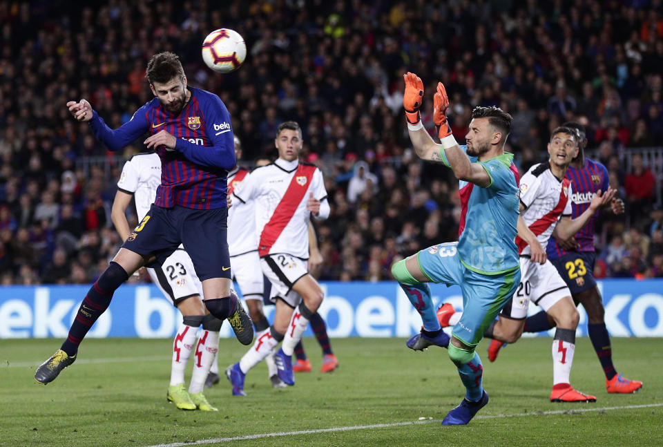 FC Barcelona's Gerard Pique, left, heads for the ball to score his side's first goal during the Spanish La Liga soccer match between FC Barcelona and Rayo Vallecano at the Camp Nou stadium in Barcelona, Spain, Saturday, March 9, 2019. (AP Photo/Manu Fernandez)