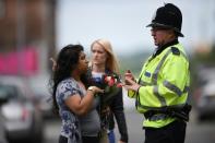 A police officer directs a woman carrying flowers near the Manchester Arena in Manchester, northwest England on May 23, 2017 following a deadly terror attack at the venue the night before