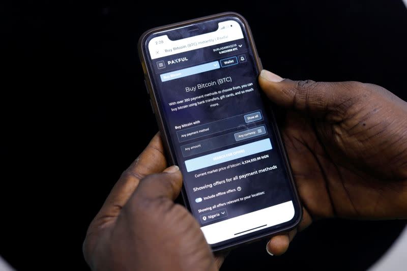 Abolaji Odunjo, a gadget vendor who trades with bitcoin, demonstrates a bitcoin application on his mobile phone after an interview with Reuters, at his store at the "Computer Village", in Lagos