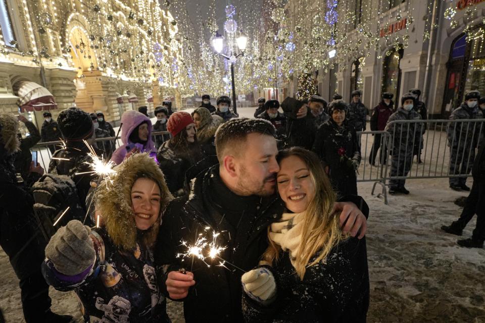 People celebrate the New Year in Nikolskaya street near an empty Red Square due to pandemic restrictions during New Year celebrations in Moscow, Russia, Saturday, Jan. 1, 2022. Russia's state coronavirus task force has registered a total of about 10.5 million confirmed infections and 308,860 deaths, but the state statistics agency that uses broader criteria in its tallying system has reported nearly 626,000 virus-linked deaths in Russia since the start of the pandemic. (AP Photo/Alexander Zemlianichenko Jr)