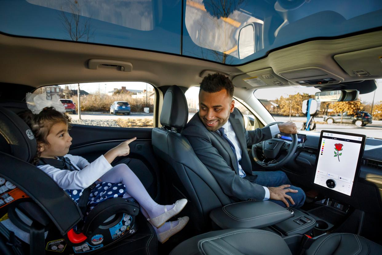 Josh Moore, a software engineer at Ford Motor Co., shows his daughter Rose how an image of a rose appears on the screen in the program he designed. The sketch app allows children to draw on the screen when the Ford vehicle is parked.