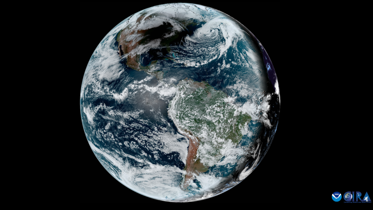  An image of earth taken by a satellite, showing white wispy clouds over blue oceans and green landmasses. 