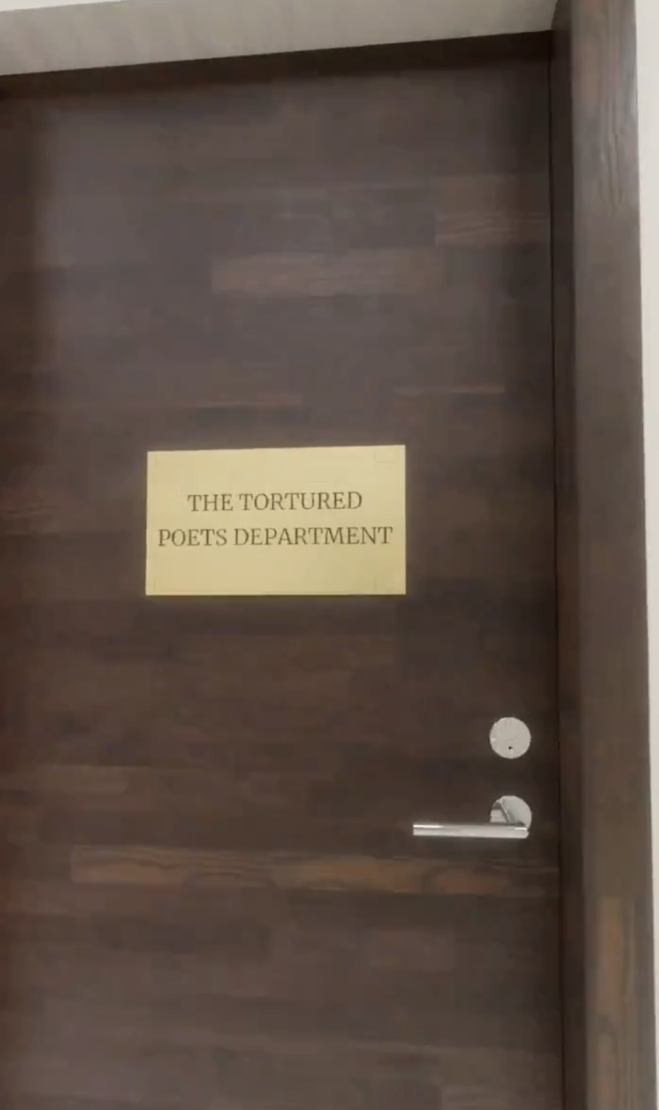 Sign on a wood door reads "THE TORTURED POETS DEPARTMENT."