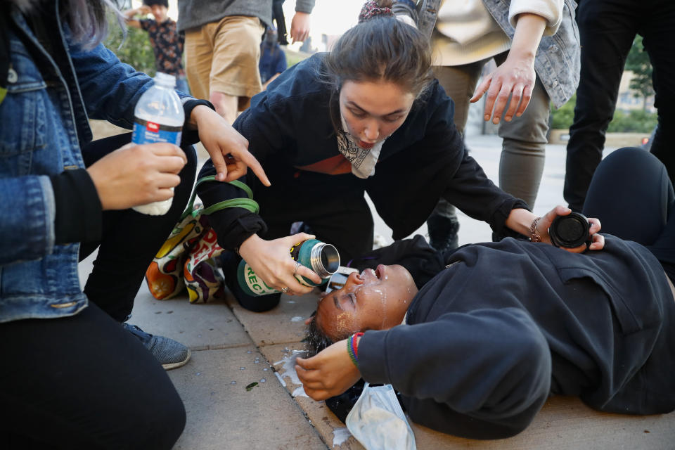 Demonstrators assist a protester who collapsed after inhaling tear gas fired by police, Friday, May 29, 2020, in St. Paul, Minn. Protests continued following the death of George Floyd, who died after being restrained by Minneapolis police officers on Memorial Day. (AP Photo/John Minchillo)