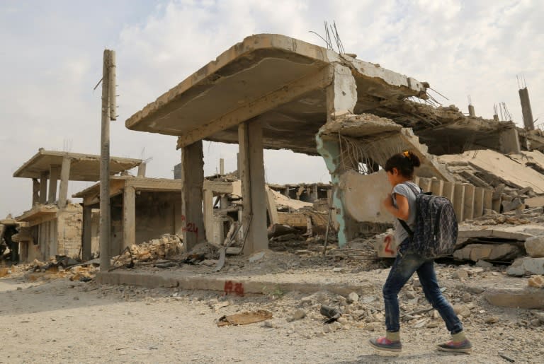 Syrian children walk past debris while heading to school on the second day of the new school year on October 6, 2015 in the Syrian Kurdish town of Kobane after Islamic State jihadists were expelled from the town in January 2015