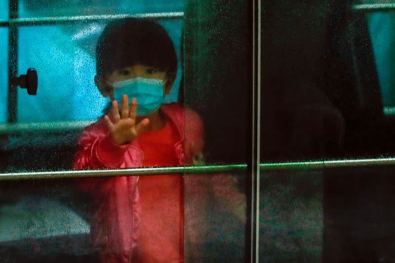 FILE PHOTO: A child waves as she sits in a vehicle carrying residents evacuated from a public housing building, following the outbreak of the novel coronavirus, outside Hong Mei House, at Cheung Hong Estate in Hong Kong