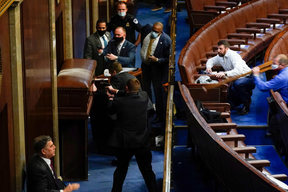 U.S. Capitol Police with guns drawn stand near a barricaded door as rioters try to break into the House Chamber at the U.S. Capitol.