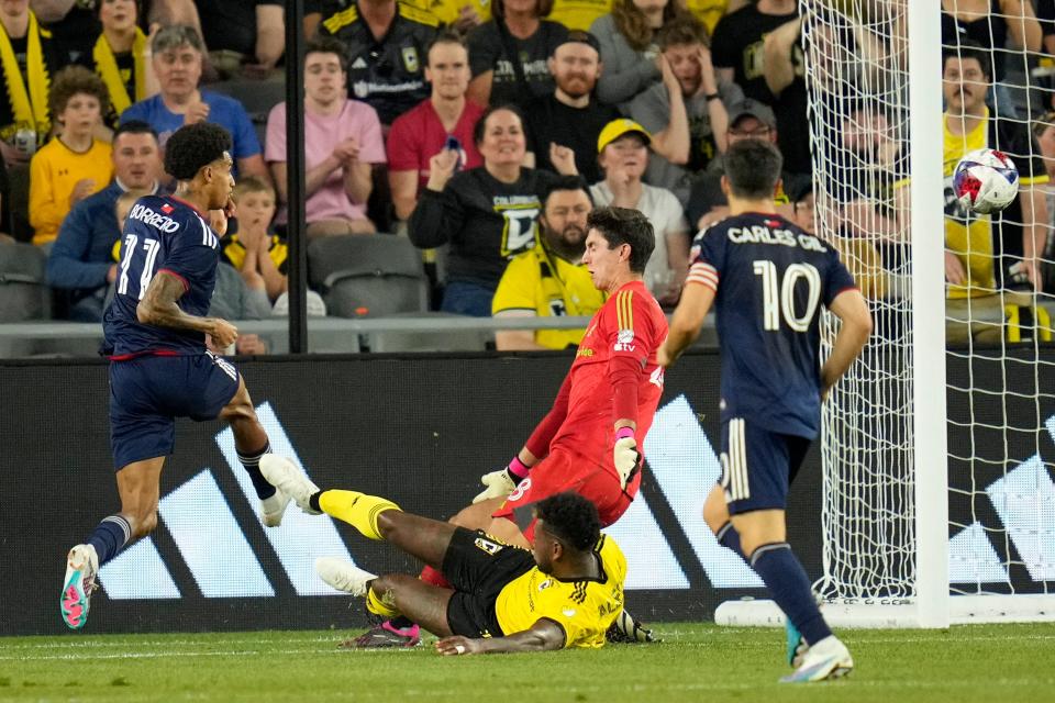 Apr 15, 2023; Columbus, Ohio, United States;  Columbus Crew’s Gustavo Vallecilla (12) and goalkeeper Patrick Schulte (28) defend a missed shot attempt by New England Revolution midfielder Dylan Borrero (11) during the first half of the MLS soccer game between Columbus Crew and New England Revolution at Lower.com Field on Saturday evening. Mandatory Credit: Joseph Scheller-The Columbus Dispatch