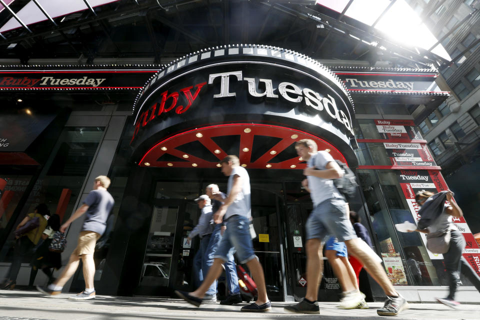 FILE - In this Sept. 16, 2016 file photo, visitors to New York's Times square walk past a Ruby Tuesday restaurant.  Ruby Tuesday is filing for bankruptcy protection, the latest casual chain to suffer from coronavirus-related closures and changing consumer habits. The Maryville, Tennessee-based company says, Wednesday, Oct. 7, 2020 its restaurants will remain open throughout the bankruptcy process.  (AP Photo/Mary Altaffer, File)