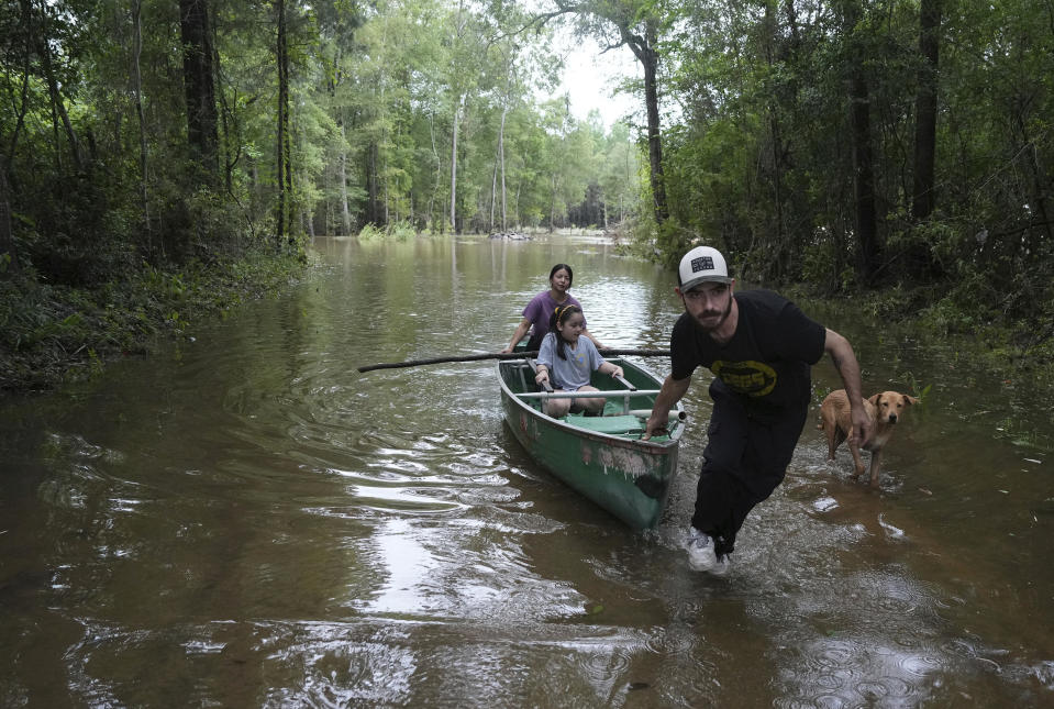 Alvaro Trevino pulls a canoe with Jennifer Tellez and Ailyn, 8, after they checked on their home on Sunday, May 5, 2024, in Spendora, Texas. The family has lived on the property in a rental trailer for two years. "It's really bad," said Tellez, who says they stayed dry during the most recent flooding in February. (Elizabeth Conley/Houston Chronicle via AP)