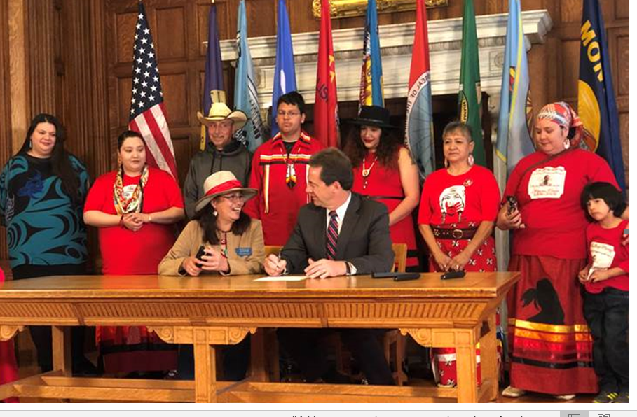 Montana Rep. Rae Peppers, D-Lame Deer, seated left, talks with Gov. Steve Bullock during a ceremonial signing  at the state Capitol of several bills dealing with missing and murdered Indigenous people. Malinda Harris and her grandson, Jeremiah, stand on the right.