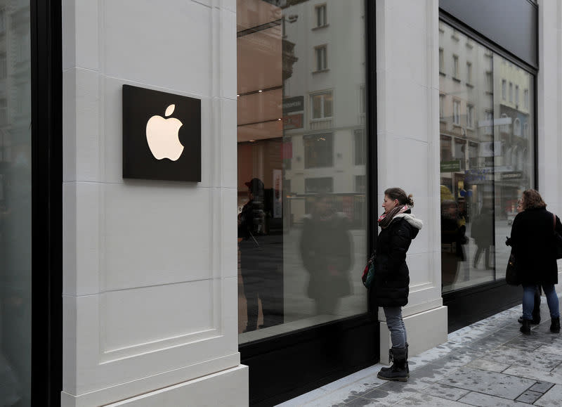 FILE PHOTO - People look into a shop window of Austria's first Apple store, which opens on February 24, during a media preview in Vienna, Austria, February 22, 2018. REUTERS/Heinz-Peter Bader