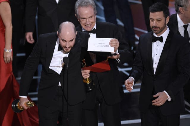 Jordan Horowitz, producer of "La La Land," shows the envelope revealing "Moonlight" as the true winner of best picture at the Oscars on Sunday, Feb. 26, 2017, at the Dolby Theatre in Los Angeles. Presenter Warren Beatty and host Jimmy Kimmel look on from right. (Photo by Chris Pizzello/Invision/AP)