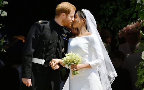 Prince Harry and Meghan Markle kiss on the steps of St George's Chapel - Credit: Ben Birchall /PA