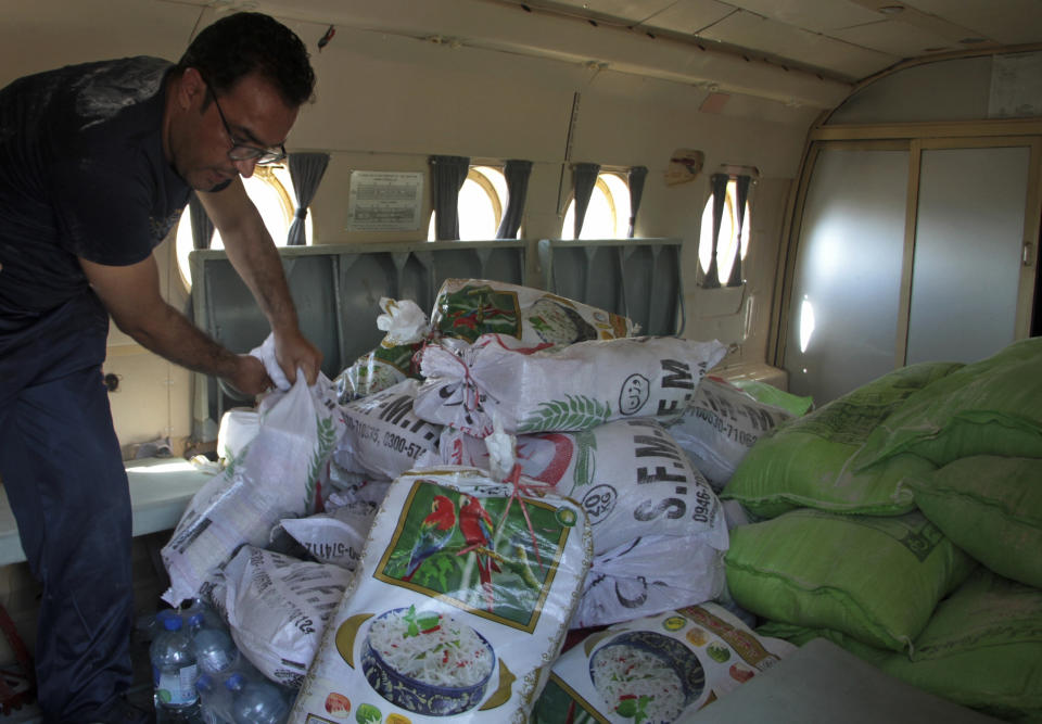 A worker loads foodstuff into a helicopter for distribution among displaced people in flood-hit areas, in Sadu Sharif, Swat Valley, Pakistan, Monday, Aug. 29, 2022. International aid was reaching Pakistan on Monday, as the military and volunteers desperately tried to evacuate many thousands stranded by widespread flooding driven by "monster monsoons" that have claimed more than 1,000 lives this summer. (AP Photo/Naveed Ali)