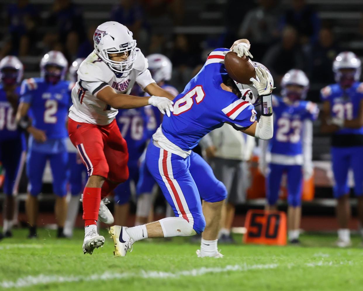 Winnacunnet's Logan Lochiatto catches the ball on the back of his head on a pass by quarterback Riley McDaniel as Memorial's AJ Sebastien defends in the first half of Friday's Division I football game in Hampton.