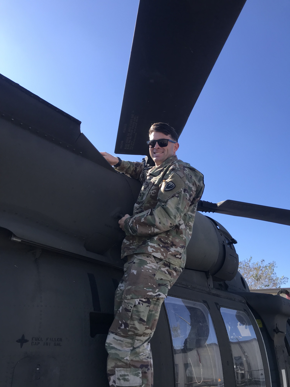 Healy hangs on the side of a Black Hawk helicopter.