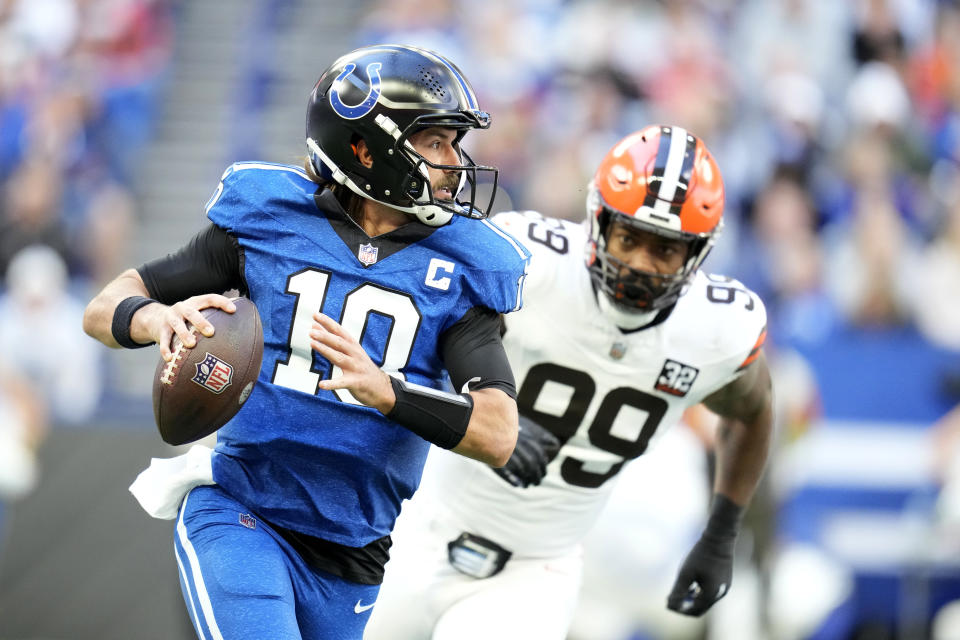 Indianapolis Colts quarterback Gardner Minshew (10) runs from Cleveland Browns defensive end Za'Darius Smith (99) during the first half of an NFL football game, Sunday, Oct. 22, 2023, in Indianapolis. (AP Photo/Michael Conroy)