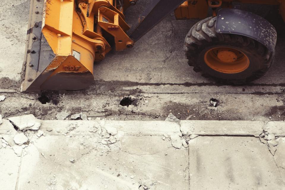 A yellow payloader performing construction on a road.