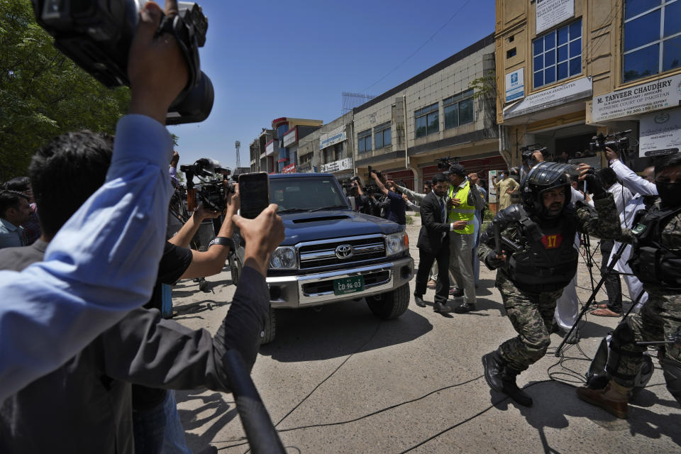 A paramilitary soldier clears the way for a vehicle carrying Pakistan's former Prime Minister Imran Khan as he arrives to appear in a court, in Islamabad, Pakistan, Friday, May 12, 2023. A high court in Islamabad has granted former Prime Minister Imran Khan a two-week reprieve from arrest in a graft case and granted him bail on the charge. (AP Photo/Anjum Naveed)