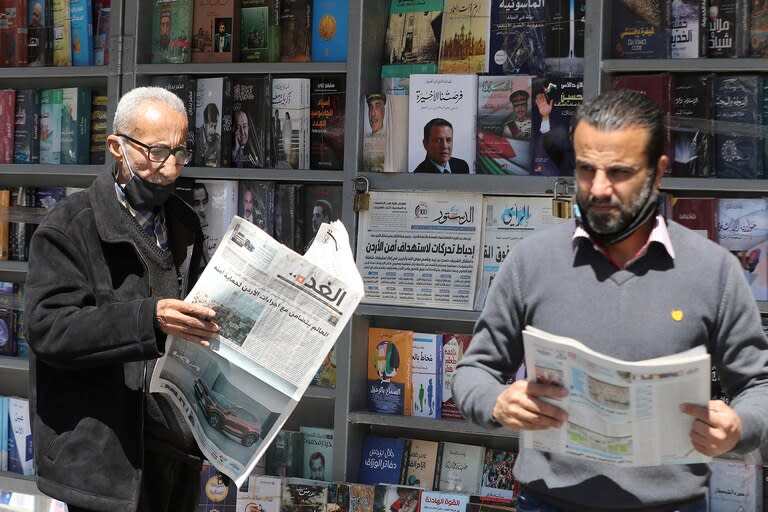 Hombres jordanos leen periódicos locales con titulares sobre los últimos eventos en su país, frente a un quiosco en la capital, Ammán, el 4 de abril de 2021