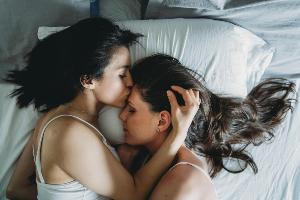 High angle view of two young adult women kissing together. One girl is kissing on the forehead the other girl. Hispanic and South American ethnicities. 