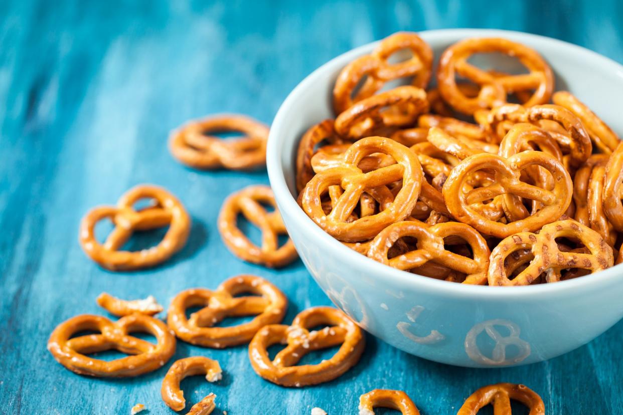 Salty snacks mini pretzels in bowl on blue wooden table