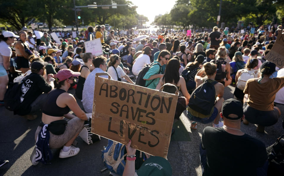 A large crowd, some with signs, including "Abortion saves lives"