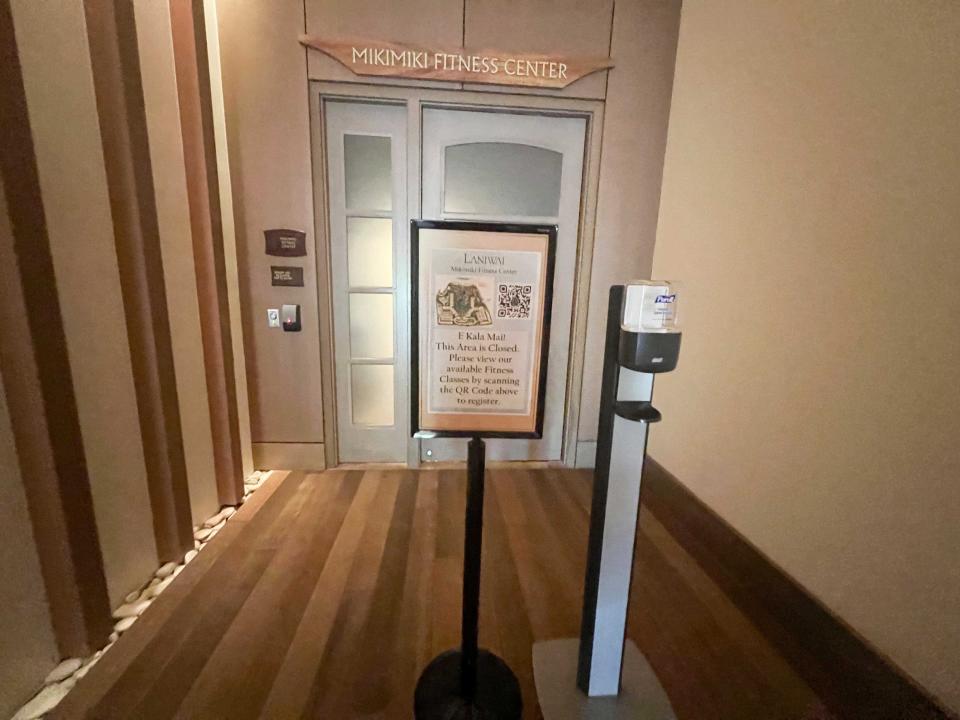 A closed door for a fitness center with a sign in front of it stating that it's closed.