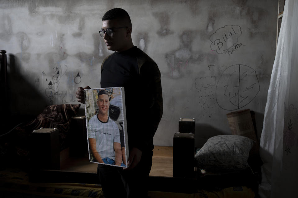 Yousef Mesheh, 15, holds a portrait of his brother, Wael in the bedroom where they were sleeping when Israeli forces stormed into their home at 3.a.m., in the Balata Refugee Camp in the northern West Bank, Tuesday, Jan. 10, 2023. They were both arrested, but Wael is still imprisoned. A report to be released next Monday by Israeli human rights organization HaMoked found that the Israeli military arrested and interrogated hundreds of Palestinian teenagers in 2022 in the occupied West Bank, without ever issuing a summons or notifying their families.(AP Photo/ Maya Alleruzzo)