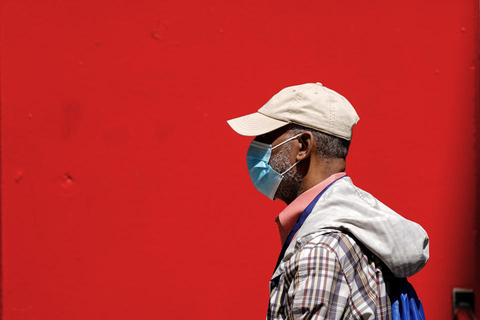 A pedestrian wearing a protective mask as a precaution against the spread of the coronavirus walks in Philadelphia, Friday, April 22, 2022. The city abandoned its indoor mask mandate Friday, just days after becoming the first U.S. metropolis to reimpose compulsory masking in response to an increase in COVID-19 cases and hospitalizations. (AP Photo/Matt Rourke)