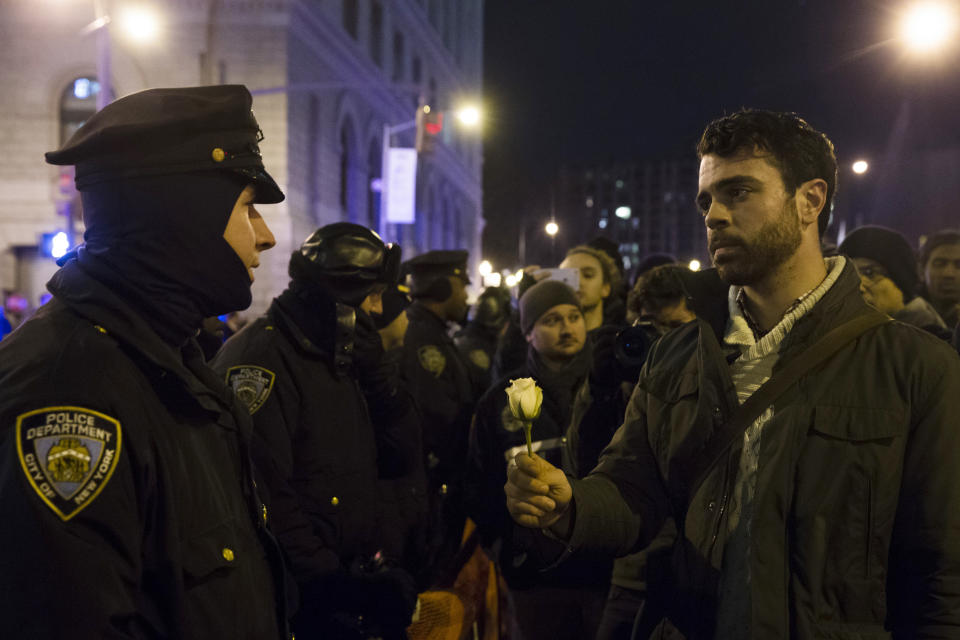 A protestor hands a police officer a flower during a march against a grand jury's decision not to indict the police officer involved in the death of Eric Garner, Thursday, Dec. 4, 2014, in the Brooklyn borough of New York. A grand jury cleared a white New York City police officer Wednesday in the videotaped chokehold death of Garner, an unarmed black man, who had been stopped on suspicion of selling loose, untaxed cigarettes. (AP Photo/John Minchillo)