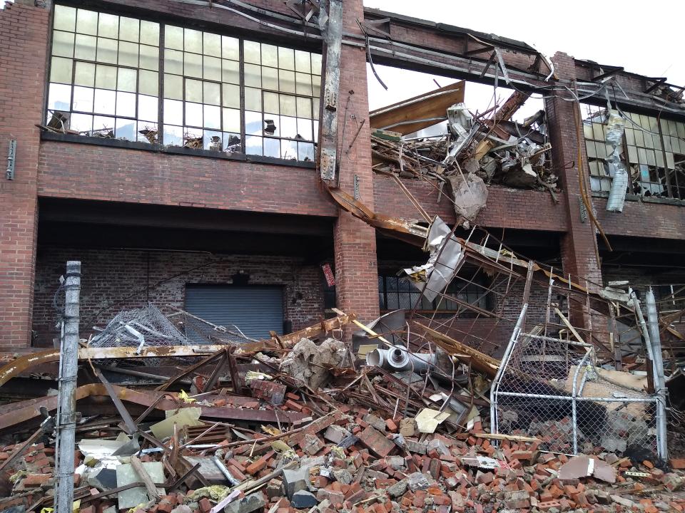 A small sign that reads “POSITIVELY NO SMOKING” dangles from the rubble of the former Goodyear Tire & Rubber Co. mixing center Saturday on River Street in Akron.