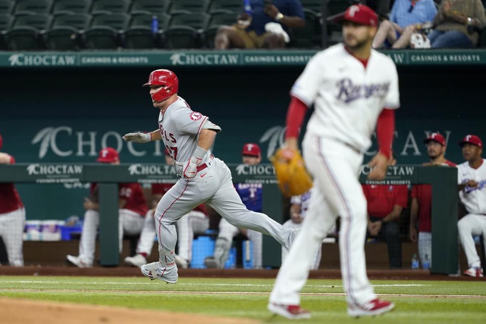 Los Angeles Angels' Mike Trout, left, sprints down the first base line on his way to a two-run double as Texas Rangers starting pitcher Martin Perez, right, looks to the outfield in the third inning of a baseball game in Arlington, Texas, Thursday, Sept. 22, 2022. (AP Photo/Tony Gutierrez)
