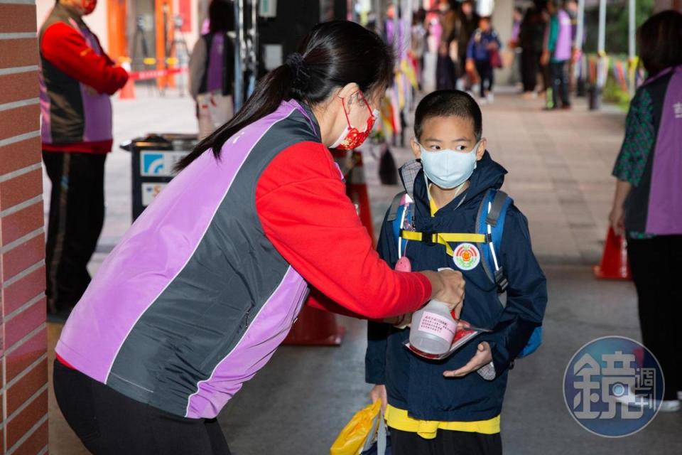 學生在進入校園前測量體溫並做好消毒工作。