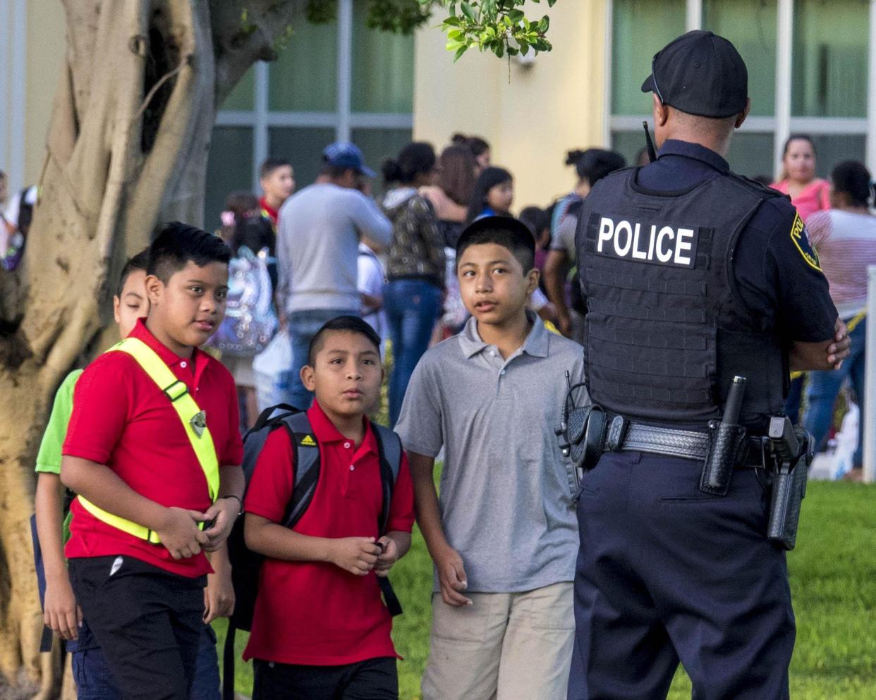 Students walk to classes past Jupiter and school district police at Jupiter Elementary School.