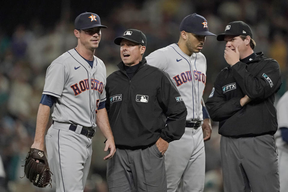 Houston Astros relief pitcher Brooks Raley, left, talks with umpire Tripp Gibson, second from left, after Raley was ejected from a baseball game against the Seattle Mariners after he hit Seattle Mariners' J.P. Crawford with a pitch during the eighth inning, Monday, July 26, 2021, in Seattle. The Mariners won 11-8. (AP Photo/Ted S. Warren)