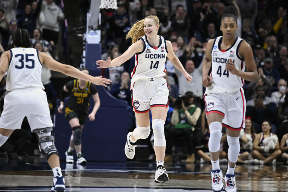 UConn's Dorka Juhasz (14) reaches for teammate Azzi Fudd's hand as she runs up court in the second half of a first-round college basketball game against Baylor in the NCAA Tournament in Storrs, Conn., March 20, 2023. Juhasz is among players headed to the draft. Even the handful of players selected in the upcoming WNBA draft will find it difficult to continue their pro careers.(AP Photo/Jessica Hill)