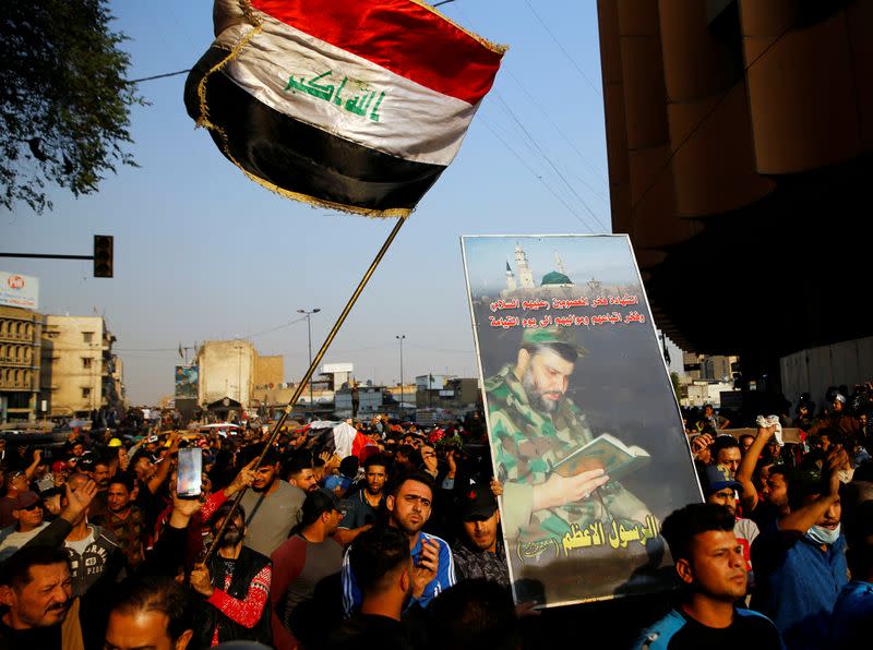 FILE PHOTO: Mourners carry a coffin of a demonstrator who was killed at an anti-government protest, while others carry an Iraqi flag and a picture of Iraqi Shi'ite cleric Moqtada al-Sadr during the funeral in Baghdad