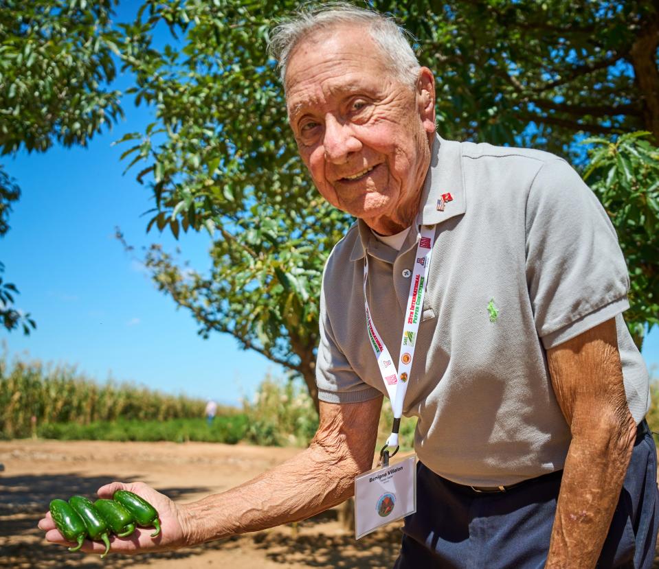 Benigno "Ben" Villalon poses for a portrait while holding some of his favorite kind of peppers during the 25th International Pepper Conference at Curry Farms in Pearce, Arizona on Tuesday, Sept. 27, 2022.