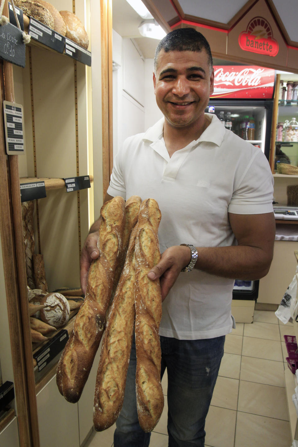 Ridha Khadher a Tunisian born baker stands in his Paris bakery, as he poses with one of his baguette, after winning the title of Best Baguette of Paris, Friday April 26, 2013. This award makes him the baguette supplier for the Elysee Palace, home of the French Presidency. (AP Photo/Remy de la Mauviniere)