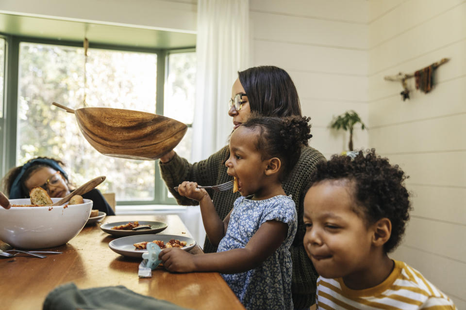 A mother serving food to her kids at the dinner table