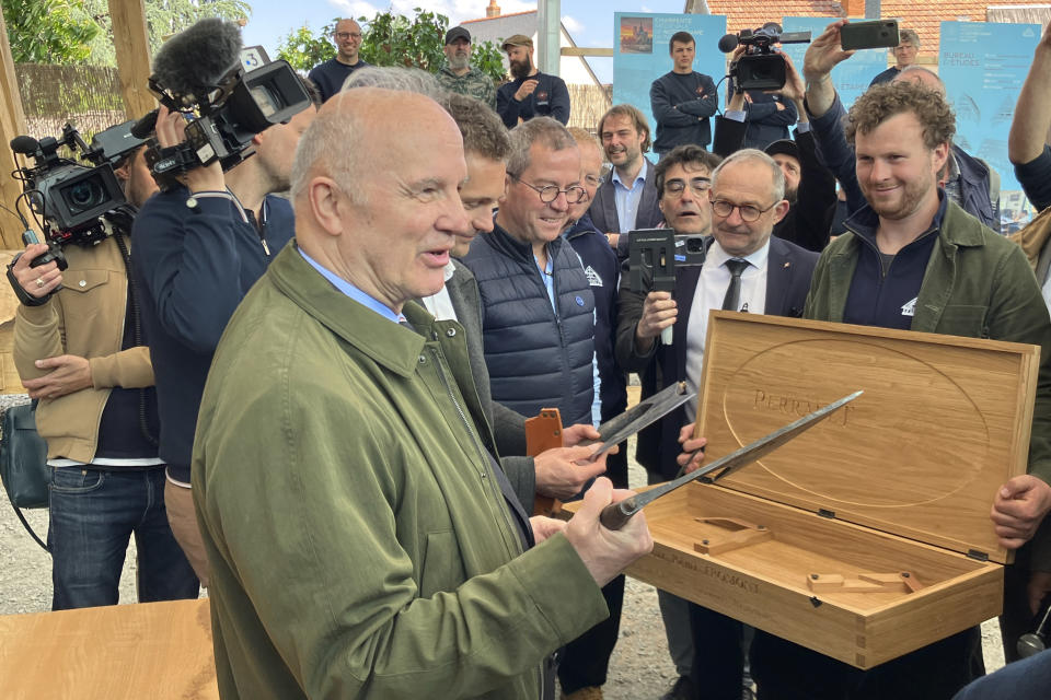 Jean-Louis Georgelin, the retired French Army general who is overseeing the Notre Dame de Paris cathedral reconstruction, holds a tool used to rebuild the roof of the Paris monument, Thursday, May, 25, 2023, near Angers, western France. The use of hand-tools to rebuild the roof that flames turned into ashes in 2019 is a deliberate, considered choice, especially since power tools would undoubtedly have done the work more quickly. The aim is to pay tribute to the astounding craftsmanship of the cathedral's original builders and to ensure that the centuries-old art of hand-fashioning wood lives on. (AP Photo/Jeffrey Schaeffer)