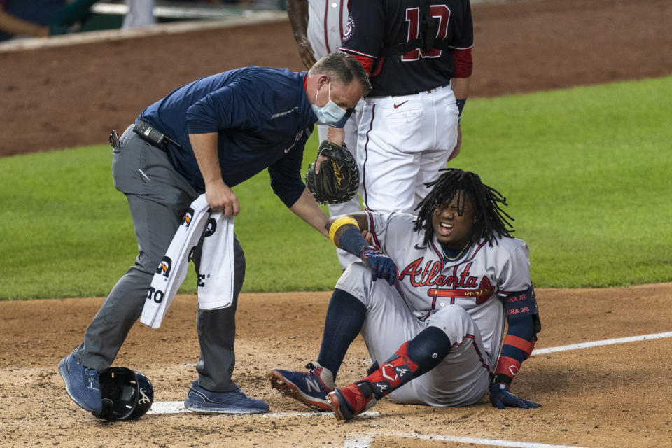 Atlanta Braves' Ronald Acuna Jr., grimaces as he is helped after fouling the ball off his left foot during the fourth inning of the team's baseball game against the Washington Nationals in Washington, Friday, Sept. 11, 2020. Acuna was helped off the field. (AP Photo/Manuel Balce Ceneta)
