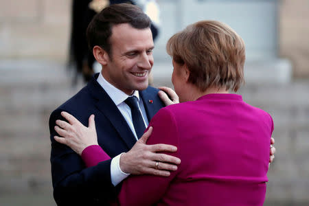 French President Emmanuel Macron (L) greets German Chancellor Angela Merkel upon her arrival at the Elysee Palace in Paris, France, January 19, 2018. REUTERS/Charles Platiau