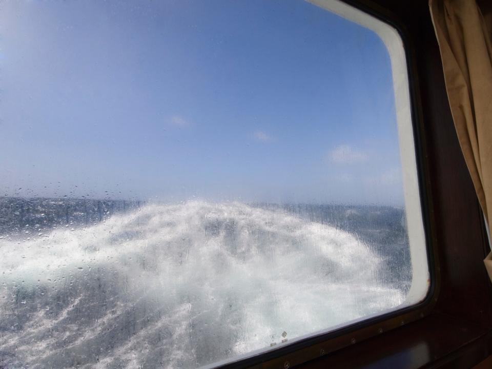 Strong waves are seen out the window of a ship.