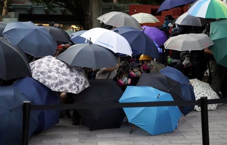 Anti-government protesters hide under umbrellas during a demonstration in Sha Tin