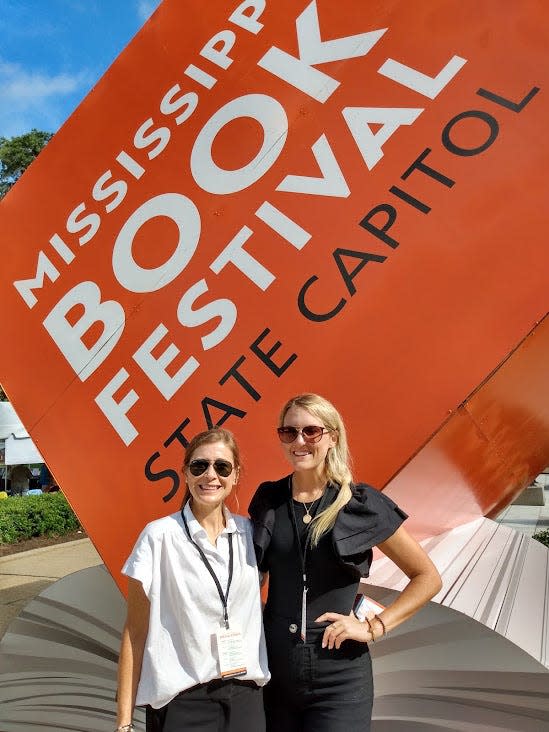 Mississippi Senate employees Kristi Ishee and Elsa Von-Dobeneck pose in front of the huge three-dimensional Mississippi Book Festival sign.