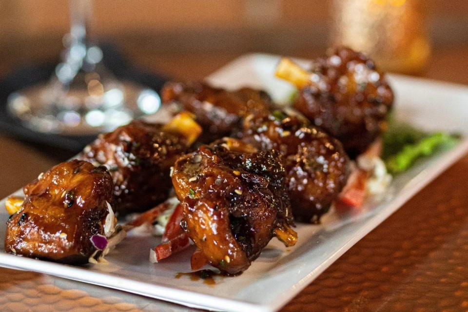 Fin & Flame Grill and Oyster Bar in Palm City features hog wings tossed in its signature Korean barbecue sauce with Asian slaw, sesame seeds and scallions.