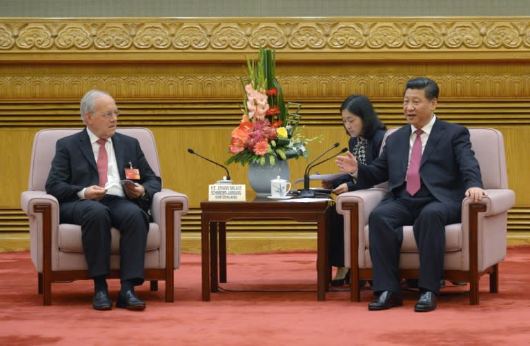 Chinese President Xi Jinping (R) speaks to Swiss Economy Minister Johann Schneider-Ammann (L) as he meets with the delegates attending the signing ceremony for the Articles of Agreement of the AIIB in Beijing on June 29, 2015